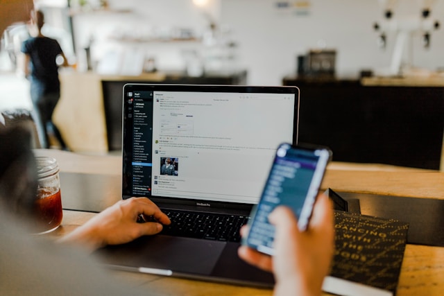 person on phone and computer desktop